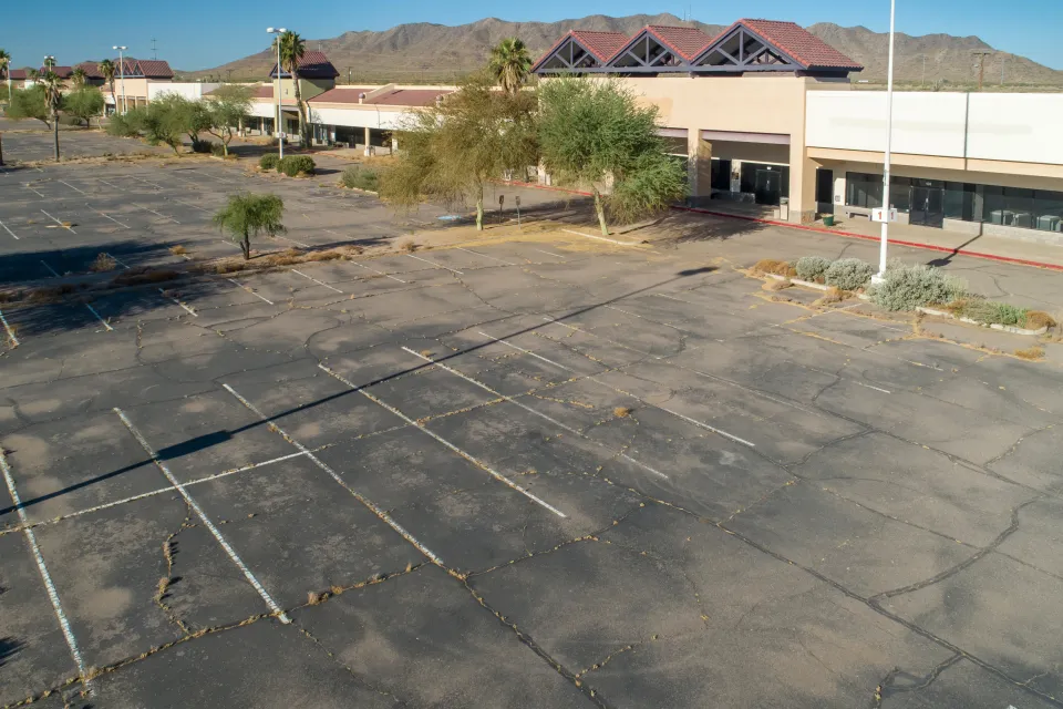 Vacant commerical parking lot in front of shuttered strip mall.